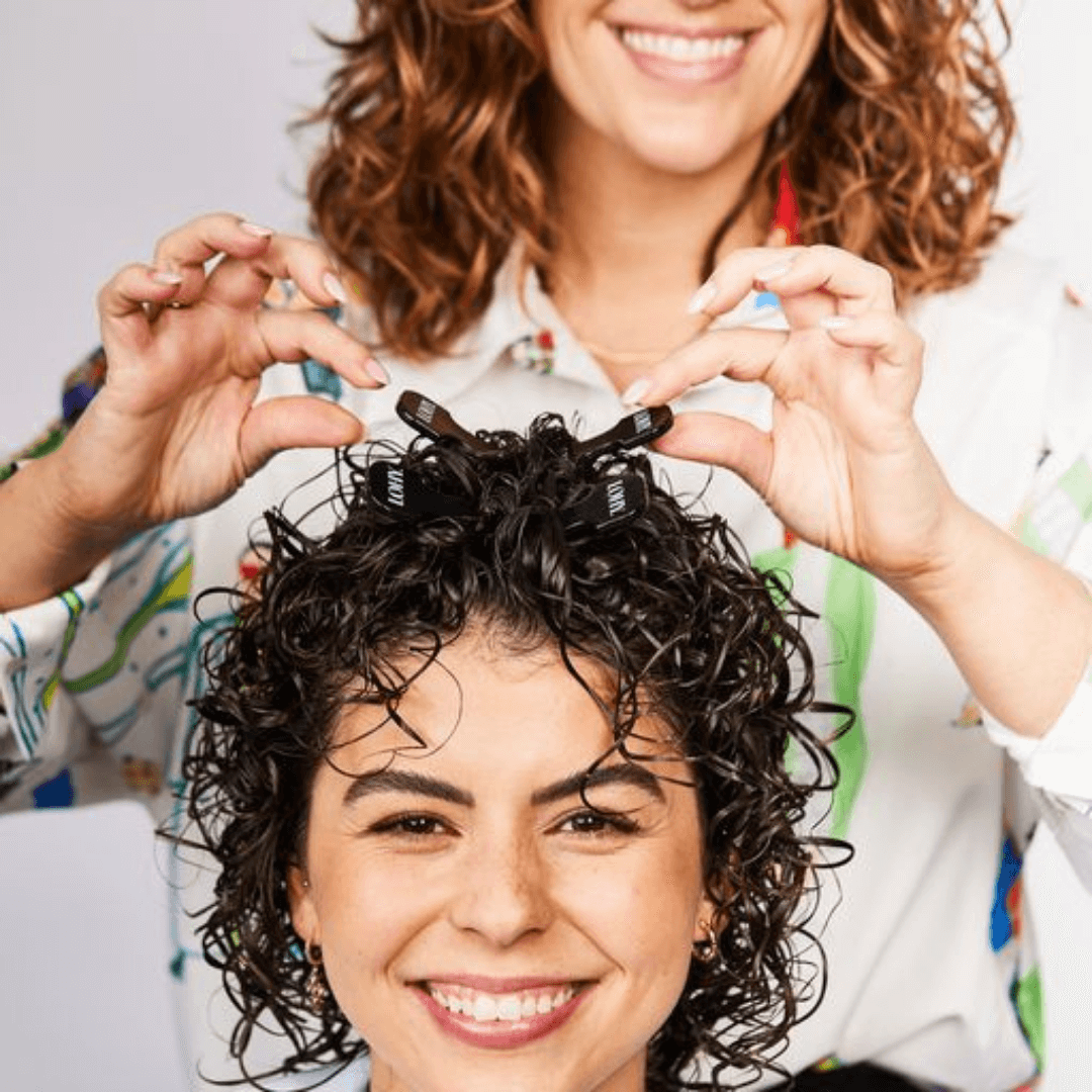 girl with short, curly brunette hair putting hair volumising combs in