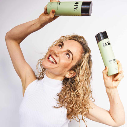 Blonde curly girl holding bottles of curl gel