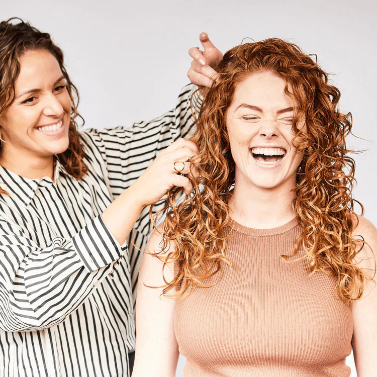 two women raking long red curly hair