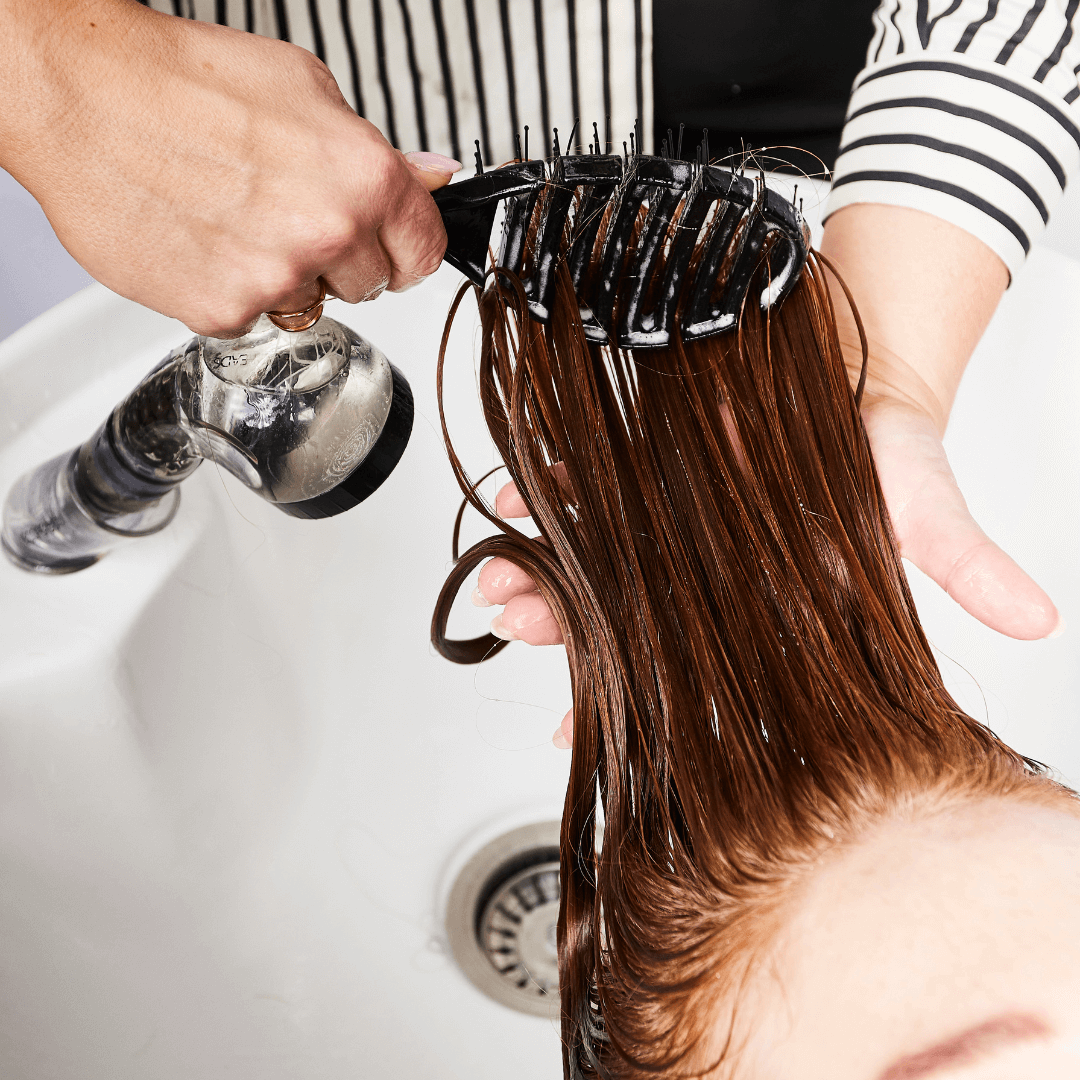 woman brushing, long red, wet, curly hair